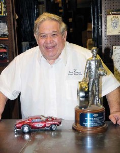 “Ohio George” stands with two of his most recognizable associations. One is a model of his ‘Mr. Gasket Gasser Mustang(one of a number of models that have been released of his vehicles) and a familiar NHRA trophy of which George has a bunch! 
