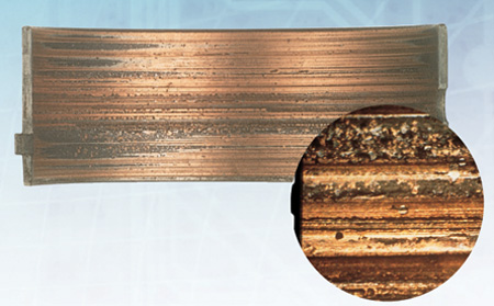 overplated copper alloy bearing gouged by cast iron debris. inset photo shows the microscopic detail of the gouges. f-m photo.
