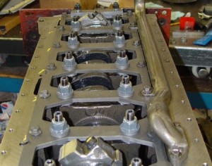 The “Gorilla Girdle” is a proprietary machined piece used to prevent main bearing cap walk by linking all of the main bearing caps together and to strengthen the block by being bolted to the oil pan rails.