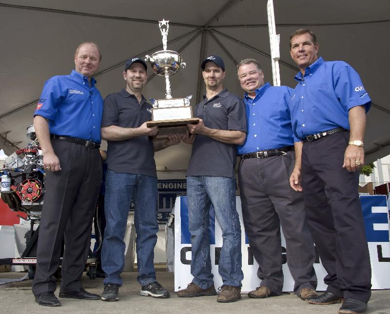 2009 MAHLE Engine Builder Showdown Champions Dennis Borem and Darrell Hoffman hold the Randy Dorton Memorial Trophy After Capturing Their Third Consecutive Title Wednesday. Shown from left to right are SPEED Analyst Larry McReynolds, Dennis Borem and Darrell Hoffman, Jesse Jones, Manager - Marketing for MAHLE Clevite and SPEED Analyst Jeff Hammond.