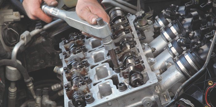 Mechanic fixing cylinder head with camshaft of car engine with socket wrench